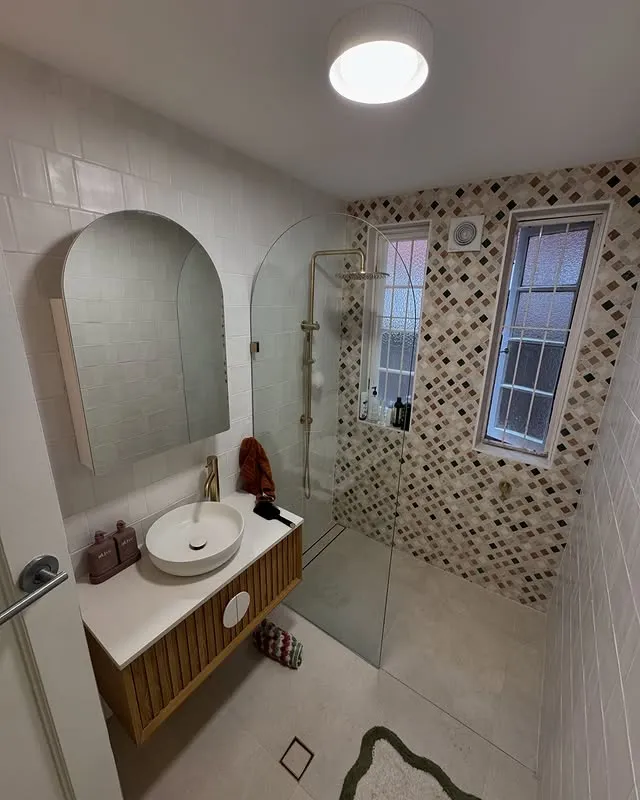 Finished modern bathroom with arched mirror and gold tapware in a Rose Bay apartment